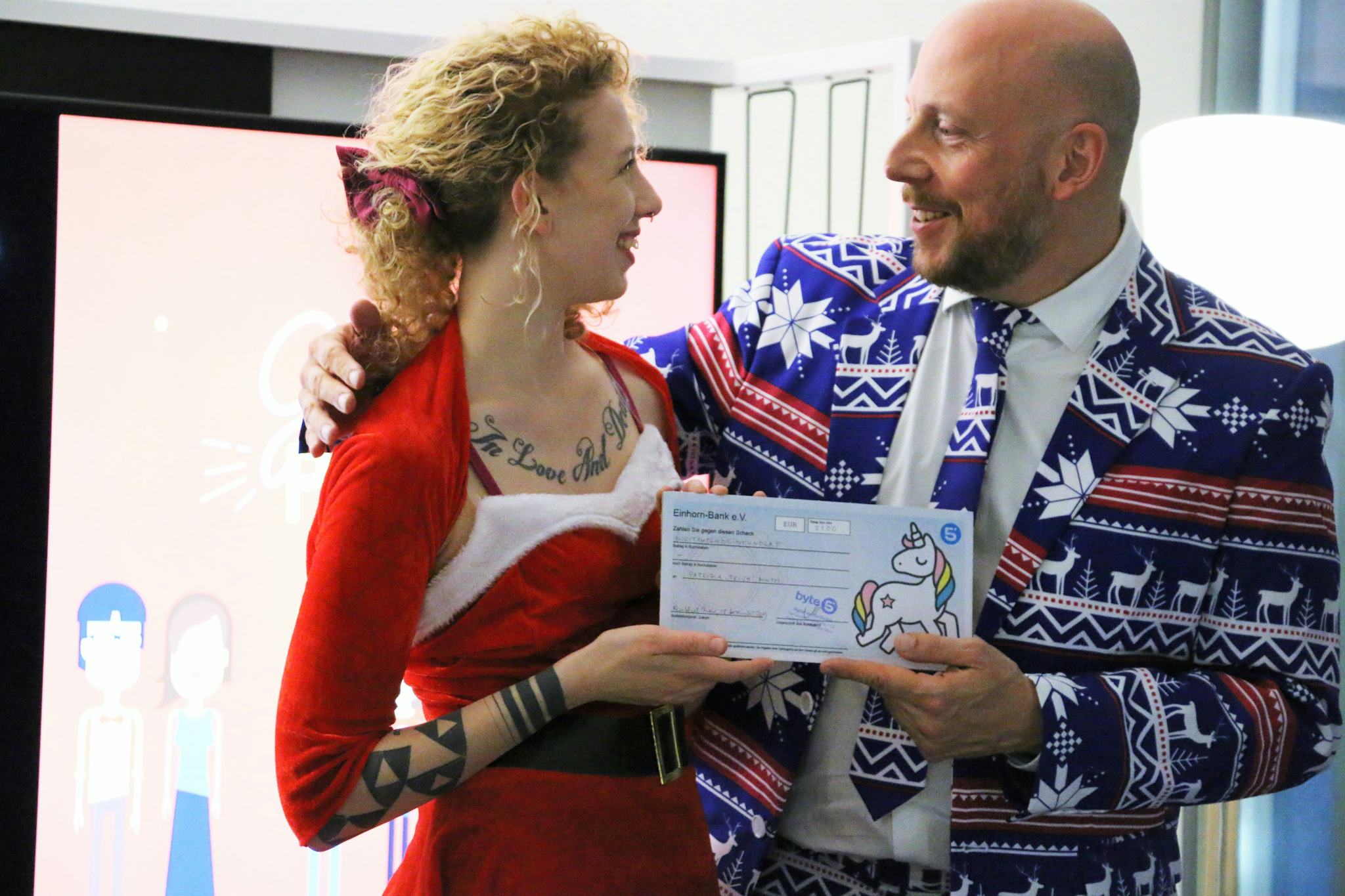 Bei der byte5-Weihnachtsfeier überreicht COO Chris Kollegin Trish einen Scheck